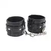 Behave! - Surrender Wrist Restraints. Czarne, wytrzymałe kajdanki z regulacją rozmiaru. Mocno połyskujący materiał